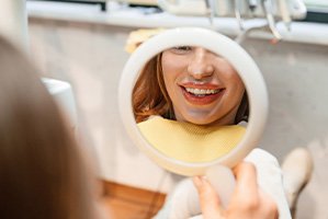 Patient with clear aligners smiling at reflection in mirror