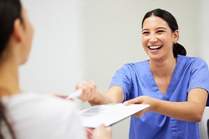 Woman smiling while handing patient form