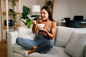 Woman sitting on sofa, eating oatmeal