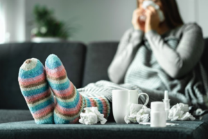 Woman sitting on the couch with a pile of tissues at her feet